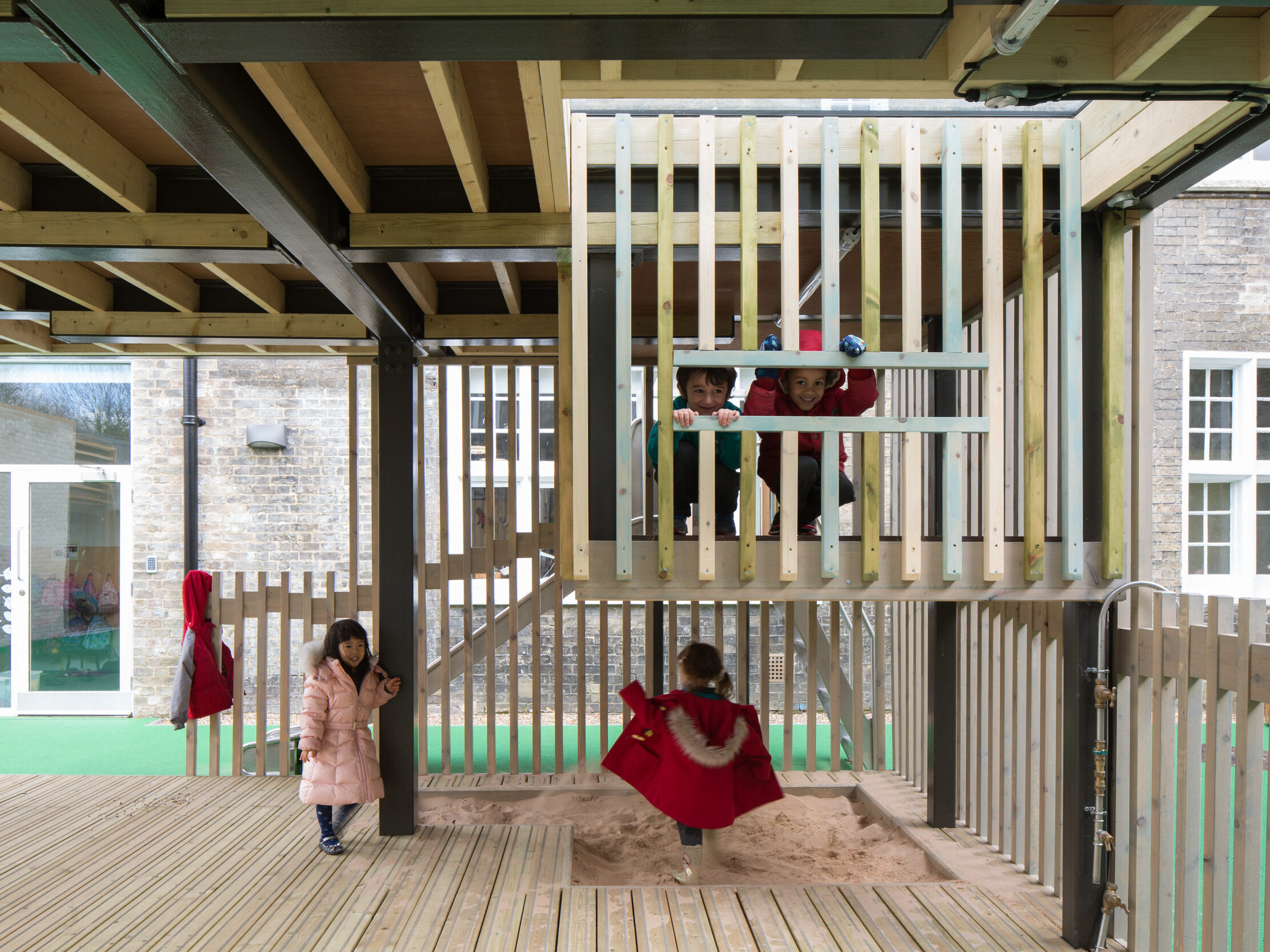 Interior of the outdoor classroom designed by CDC studios, with wooden balustrades, floor, and sandpit.