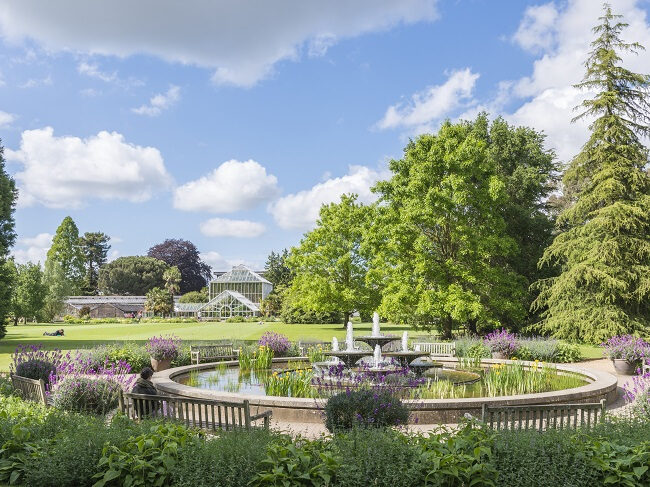 Water fountain designed by David Mellor, with field and Plant House in the background. | The Rising Path, Cambridge University Botanic Garden by architects CDC Studio